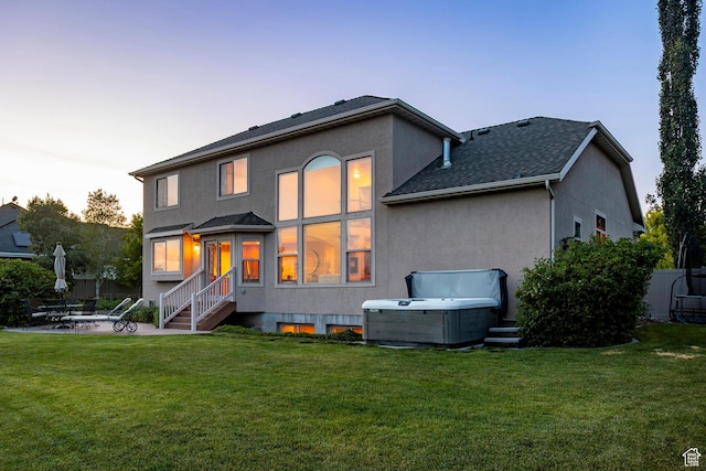 4179 W Sandalwood Dr, Cedar Hills, UT 84062 - back of house at dusk featuring stucco siding, a patio area, a yard, and roof with shingles