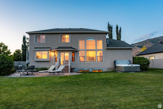 4179 W Sandalwood Dr, Cedar Hills, UT 84062 - back of property at dusk with a hot tub, stucco siding, a patio area, entry steps, and roof with shingles