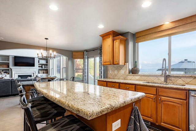 4179 W Sandalwood Dr, Cedar Hills, UT 84062 - kitchen with a kitchen island, decorative backsplash, a kitchen bar, a chandelier, and light stone countertops