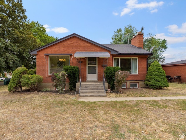 2335 Fillmore Ave, Ogden, UT 84401 - view of front of house featuring a front yard, a chimney, and brick siding