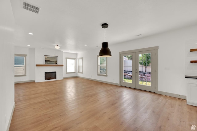 4961 E Oakwood Dr, Eagle Mountain, UT 84005 - unfurnished living room with plenty of natural light, light wood-style flooring, a fireplace, recessed lighting, and french doors