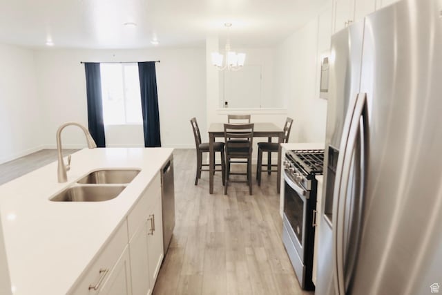 54 N Heading Row, Saratoga Springs, UT 84045 - kitchen with appliances with stainless steel finishes, light wood-style flooring, white cabinetry, a chandelier, and pendant lighting