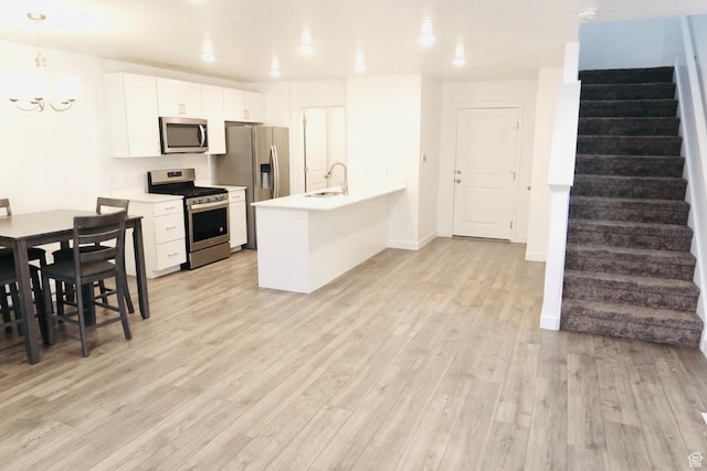 54 N Heading Row, Saratoga Springs, UT 84045 - kitchen with stainless steel appliances, a chandelier, light wood finished floors, light countertops, and a peninsula