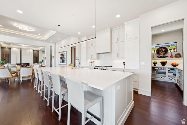 13690 N Deer Canyon Dr, Kamas, UT 84036 - kitchen featuring dark wood finished floors, a spacious island, a kitchen breakfast bar, white cabinets, and custom exhaust hood