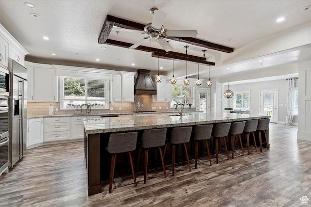 2718 N 2125 E, Layton, UT 84040 - kitchen with custom exhaust hood, light wood-type flooring, a large island, tasteful backsplash, and plenty of natural light