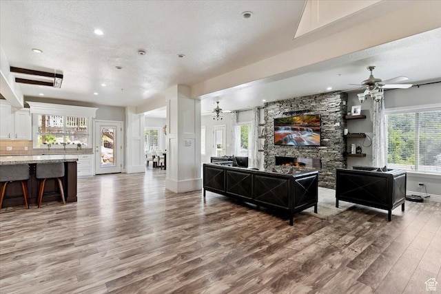 2718 N 2125 E, Layton, UT 84040 - living room featuring a ceiling fan, light wood-type flooring, a stone fireplace, plenty of natural light, and recessed lighting