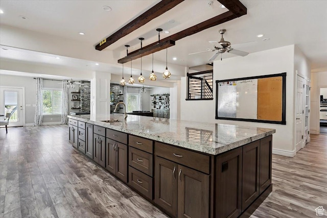 2718 N 2125 E, Layton, UT 84040 - kitchen featuring light wood-style flooring, dark brown cabinetry, a ceiling fan, beamed ceiling, and light stone counters