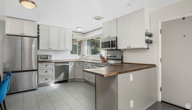 985 Jackson Ave, Ogden, UT 84404 - kitchen with stainless steel appliances, a peninsula, tasteful backsplash, wooden counters, and light tile patterned floors
