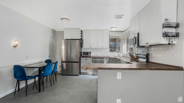 985 Jackson Ave, Ogden, UT 84404 - kitchen with appliances with stainless steel finishes, decorative backsplash, white cabinets, and a peninsula