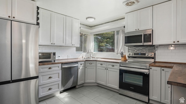 985 Jackson Ave, Ogden, UT 84404 - kitchen featuring stainless steel appliances, wooden counters, light tile patterned flooring, and decorative backsplash
