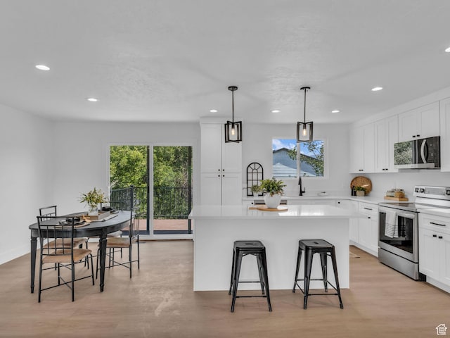6685 S 3380 W, West Jordan, UT 84084 - kitchen featuring stainless steel appliances, recessed lighting, a kitchen island, a breakfast bar, and white cabinetry