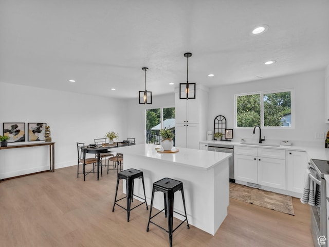 6685 S 3380 W, West Jordan, UT 84084 - kitchen featuring appliances with stainless steel finishes, light wood-type flooring, a breakfast bar, white cabinetry, and plenty of natural light