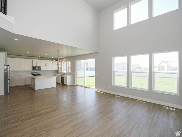 928 E Blackfeet Dr, Eagle Mountain, UT 84005 - unfurnished living room featuring a chandelier, dark wood-style flooring, and a towering ceiling