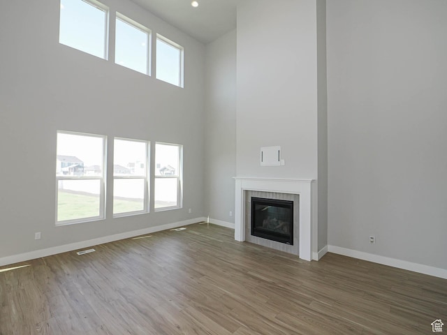 928 E Blackfeet Dr, Eagle Mountain, UT 84005 - unfurnished living room with wood finished floors, a tiled fireplace, a towering ceiling, and recessed lighting
