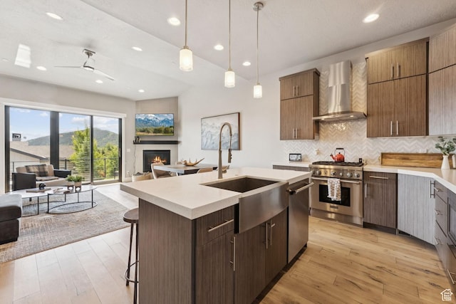 4313 Holly Frost Ct, Park City, UT 84098 - kitchen with wall chimney range hood, appliances with stainless steel finishes, open floor plan, light countertops, and a glass covered fireplace