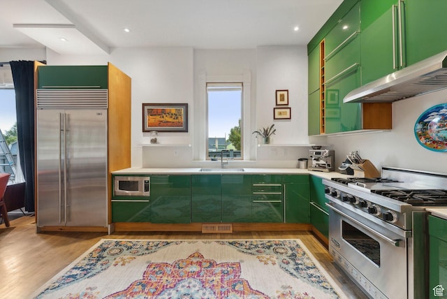 853 E Second Ave N, Salt Lake City, UT 84103 - kitchen with built in appliances, green cabinets, light wood-style flooring, wall chimney range hood, and light countertops