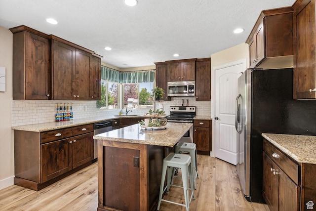 6082 W Cedar Fork Dr S, West Jordan, UT 84081 - kitchen with appliances with stainless steel finishes, light wood finished floors, a center island, a kitchen bar, and recessed lighting