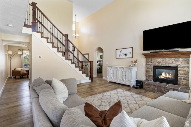 6082 W Cedar Fork Dr S, West Jordan, UT 84081 - living room with arched walkways, wood finished floors, a stone fireplace, a towering ceiling, and stairway