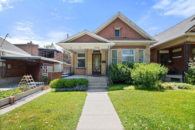 320 E 3rd Ave, Salt Lake City, UT 84103 - view of front of house with covered porch, a front yard, brick siding, and a vegetable garden