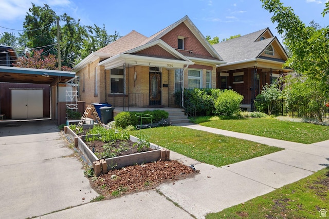 320 E 3rd Ave, Salt Lake City, UT 84103 - view of front of property with a vegetable garden, a front lawn, brick siding, covered porch, and driveway
