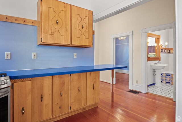 320 E 3rd Ave, Salt Lake City, UT 84103 - kitchen featuring stainless steel stove, wood finished floors, and a breakfast bar area