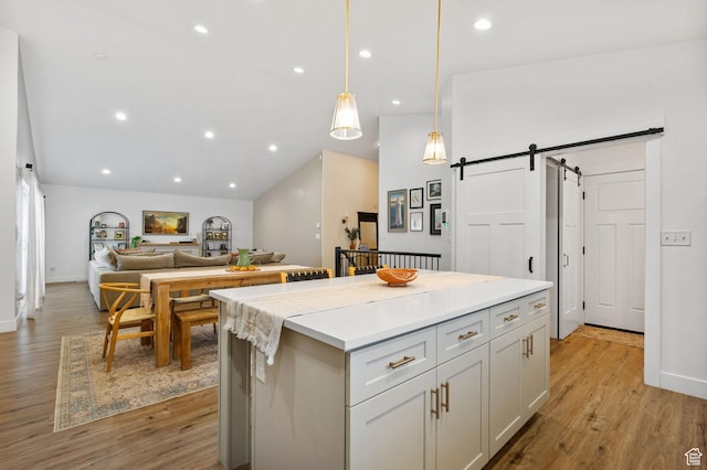 2418 E Quaking Aspen Ln, Eagle Mountain, UT 84005 - kitchen with a barn door, a kitchen island, light wood-style floors, open floor plan, and decorative light fixtures