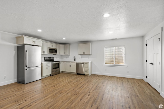2418 E Quaking Aspen Ln, Eagle Mountain, UT 84005 - kitchen with stainless steel appliances, a textured ceiling, light wood-style flooring, light countertops, and recessed lighting