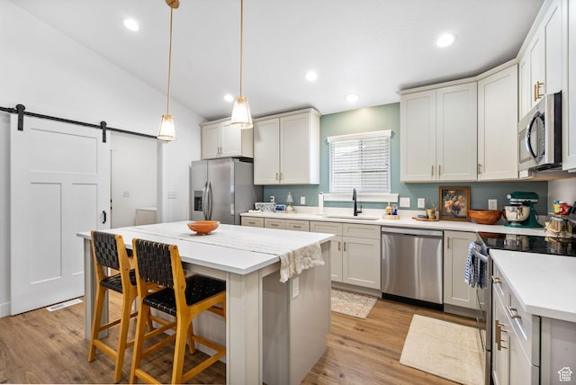 2418 E Quaking Aspen Ln, Eagle Mountain, UT 84005 - kitchen featuring stainless steel appliances, a barn door, a kitchen bar, a kitchen island, and light wood-style floors