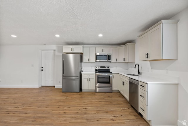 2418 E Quaking Aspen Ln, Eagle Mountain, UT 84005 - kitchen with appliances with stainless steel finishes, recessed lighting, light wood-style flooring, a textured ceiling, and light countertops
