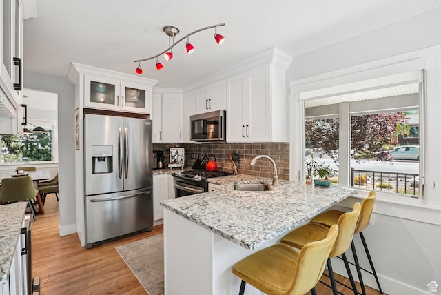 3232 S 2600 E, Salt Lake City, UT 84109 - kitchen featuring stainless steel appliances, tasteful backsplash, white cabinets, a peninsula, and light stone counters