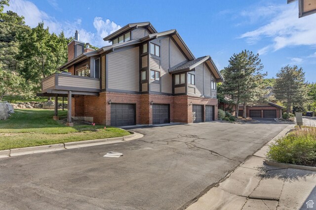 7430 S Wasatch Blvd E Unit I-2, Cottonwood Heights, UT 84121 - view of side of property with brick siding, an attached garage, a chimney, a yard, and driveway