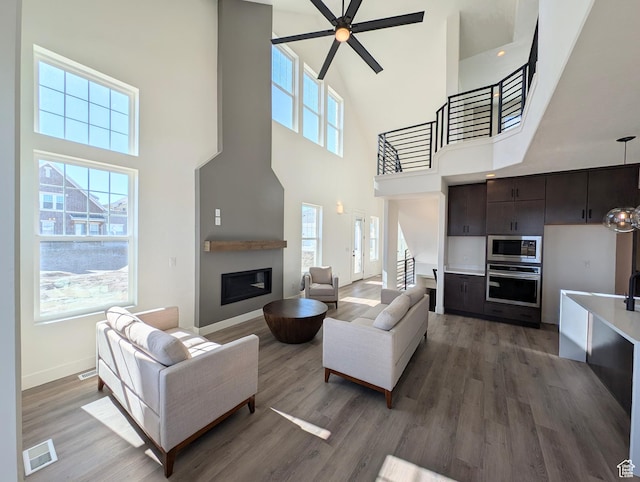 11369 S Watercourse Rd W Unit 202, South Jordan, UT 84009 - living area with a high ceiling, wood finished floors, a glass covered fireplace, ceiling fan, and stairs