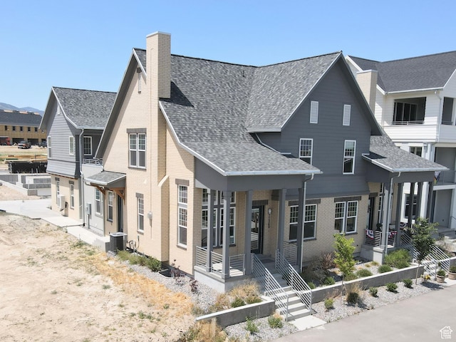 11369 S Watercourse Rd W Unit 202, South Jordan, UT 84009 - view of front facade with a chimney, brick siding, roof with shingles, and a porch