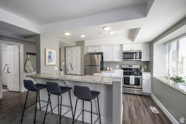 2220 E Murray Holladay Rd S Unit 75, Salt Lake City, UT 84117 - kitchen with appliances with stainless steel finishes, dark wood-style floors, and a kitchen bar
