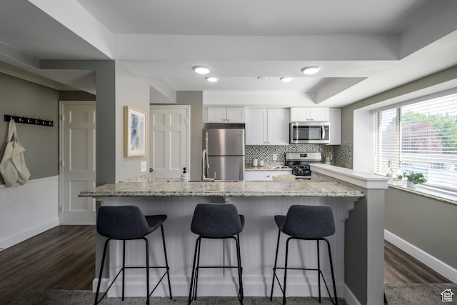 2220 E Murray Holladay Rd S Unit 75, Salt Lake City, UT 84117 - kitchen featuring appliances with stainless steel finishes, dark wood-style floors, a breakfast bar area, and white cabinetry