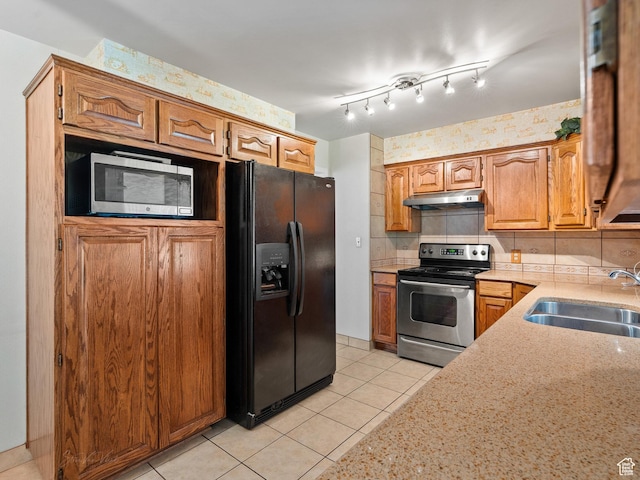 320 S 2nd St W, Soda Springs, ID 83276 - kitchen featuring stainless steel appliances, under cabinet range hood, light tile patterned floors, brown cabinetry, and light stone counters