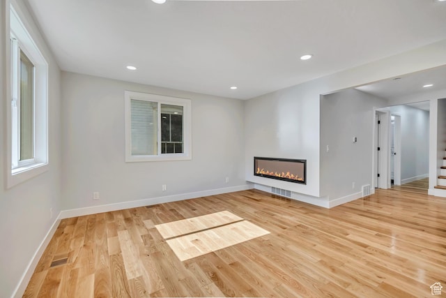 1804 S Park St, Salt Lake City, UT 84105 - unfurnished living room with light wood-style flooring, a glass covered fireplace, and recessed lighting