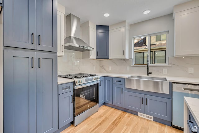 1804 S Park St, Salt Lake City, UT 84105 - kitchen with wall chimney range hood, stainless steel appliances, light countertops, light wood-type flooring, and backsplash