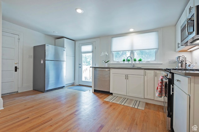 662 E 4th Ave, Salt Lake City, UT 84103 - kitchen featuring appliances with stainless steel finishes, dark countertops, light wood-type flooring, white cabinetry, and recessed lighting