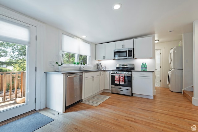 662 E 4th Ave, Salt Lake City, UT 84103 - kitchen featuring appliances with stainless steel finishes, stacked washer / drying machine, white cabinetry, light wood-type flooring, and recessed lighting