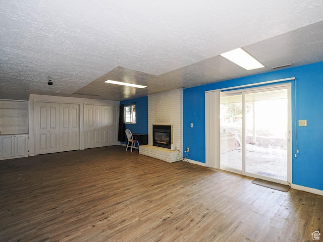 4060 W 2550 S, Taylor, UT 84401 - unfurnished living room with wood finished floors, a brick fireplace, and a textured ceiling