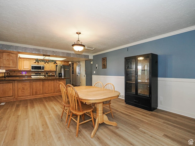 4060 W 2550 S, Taylor, UT 84401 - dining area featuring crown molding, light wood-type flooring, a textured ceiling, and a wainscoted wall