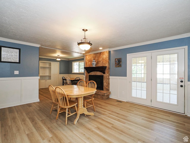 4060 W 2550 S, Taylor, UT 84401 - dining room with light wood finished floors, a decorative wall, a textured ceiling, crown molding, and a wainscoted wall