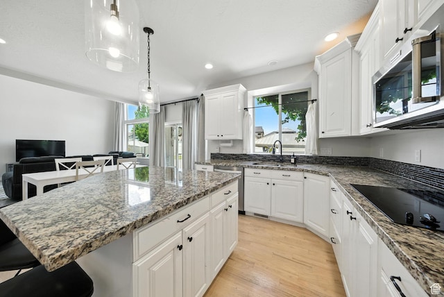 3072 W Current Creek Dr, South Jordan, UT 84095 - kitchen featuring stainless steel appliances, a kitchen island, a breakfast bar area, light wood finished floors, and white cabinets