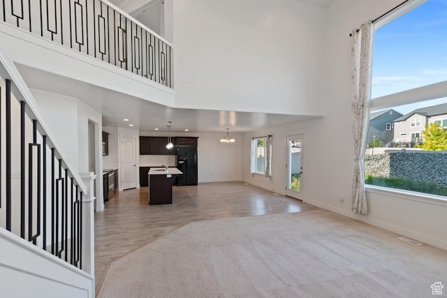194 N Valcrest Dr, Saratoga Springs, UT 84045 - unfurnished living room featuring light carpet, a chandelier, a towering ceiling, light wood finished floors, and recessed lighting