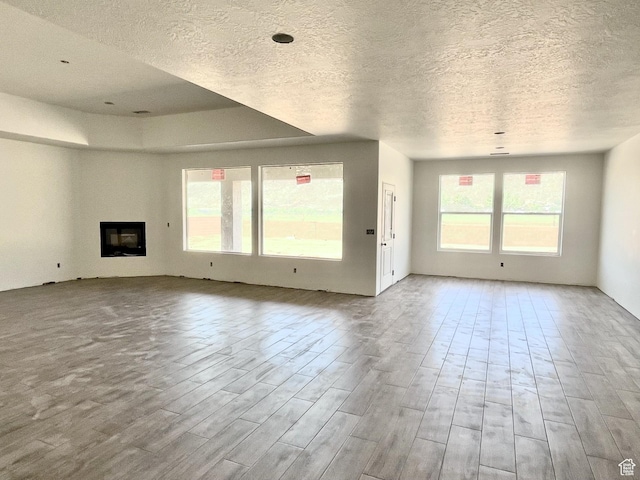 1843 S 920 W, Hurricane, UT 84737 - unfurnished living room featuring a textured ceiling, plenty of natural light, wood finished floors, and a glass covered fireplace