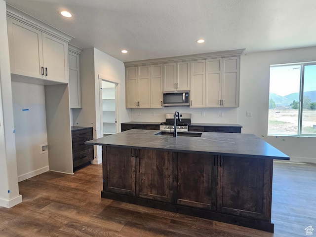 2804 W 2710 N Unit 87, Plain City, UT 84404 - kitchen featuring stainless steel microwave, dark countertops, dark wood-style flooring, an island with sink, and recessed lighting