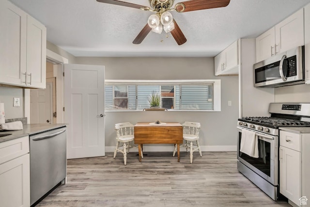 2056 Liberty Ave, Ogden, UT 84401 - kitchen with appliances with stainless steel finishes, ceiling fan, light wood-style flooring, white cabinets, and light countertops