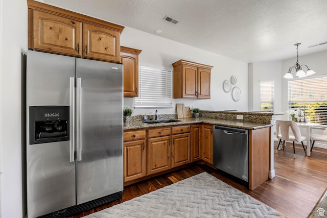 3315 W Birch Creek Rd S Unit 28D, West Haven, UT 84401 - kitchen featuring stainless steel appliances, a peninsula, a chandelier, brown cabinetry, and dark stone counters