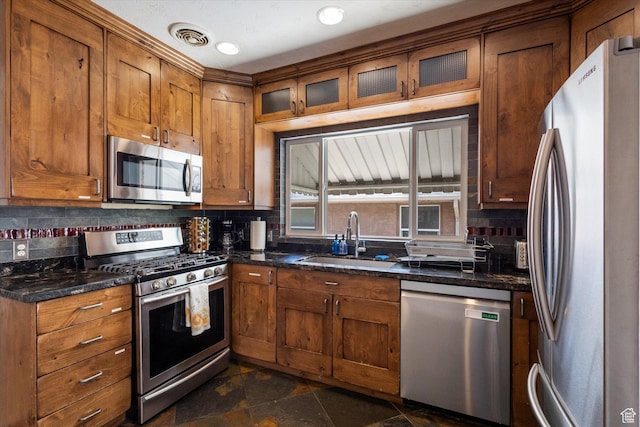 1143 E 1300 S, Salt Lake City, UT 84105 - kitchen featuring appliances with stainless steel finishes, tasteful backsplash, brown cabinets, glass insert cabinets, and dark stone finish floors